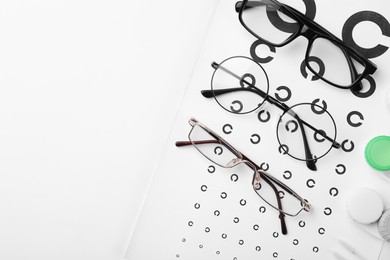 Vision test chart, glasses and lenses on white background, flat lay. Space for text