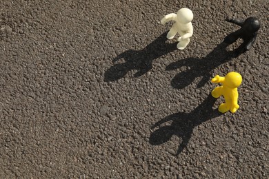 Many plasticine human figures on asphalt road outdoors, above view. Space for text