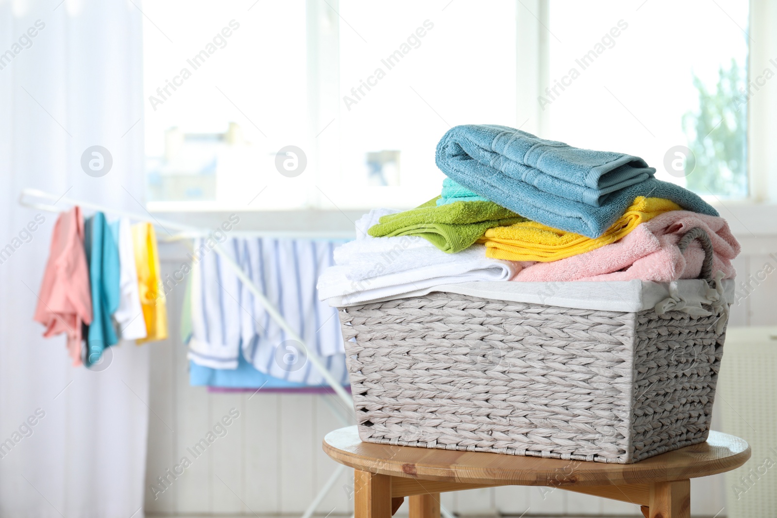 Photo of Basket with clean laundry on table at home, space for text