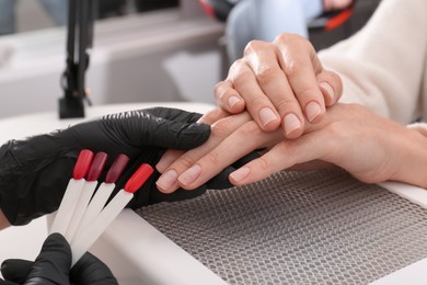 Photo of Professional manicurist working with client in salon, closeup