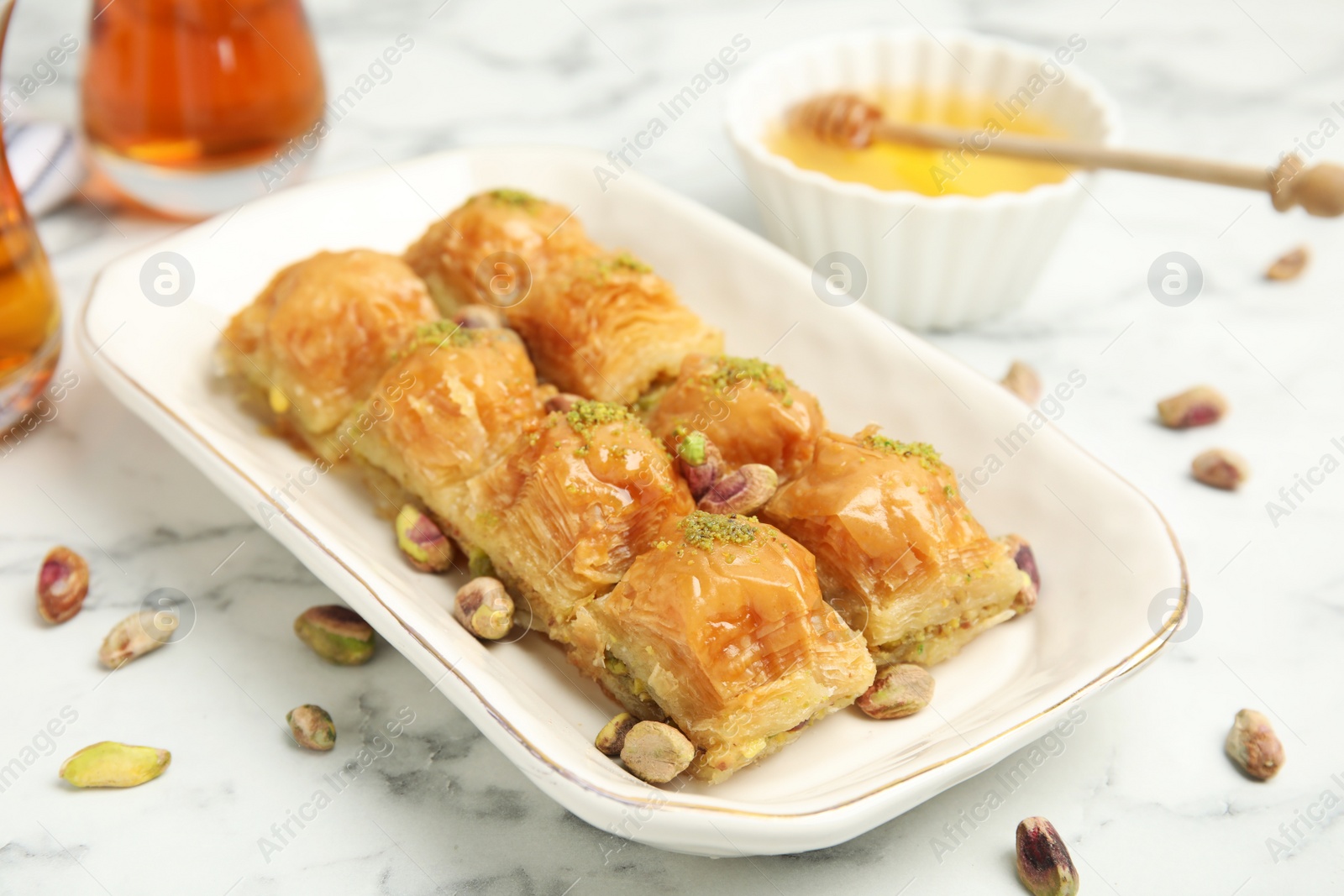 Photo of Delicious baklava with pistachios and scattered nuts on white marble table