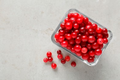 Photo of Cranberries in bowl on light grey table, top view. Space for text