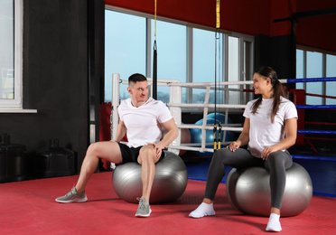 Couple working out on fit balls in gym
