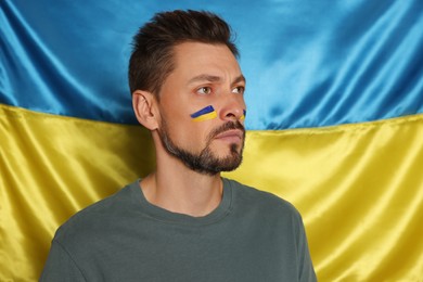 Photo of Man with face paint near Ukrainian flag