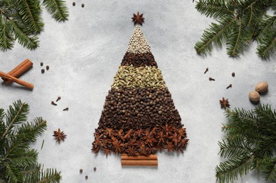 Photo of Christmas tree made of different spices and fir branches on gray textured table, flat lay