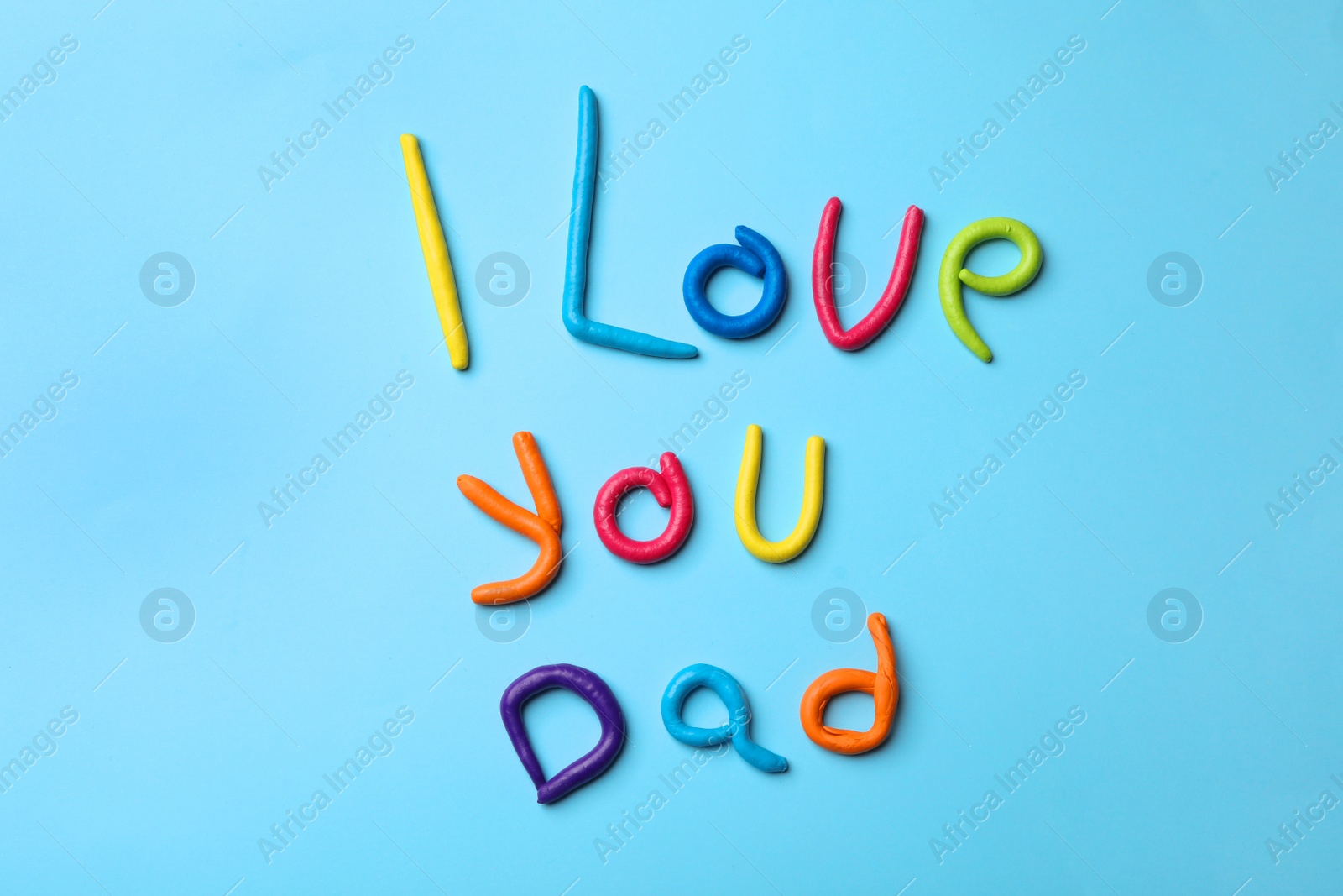 Photo of Phrase I LOVE YOU DAD made of plasticine on color background, top view