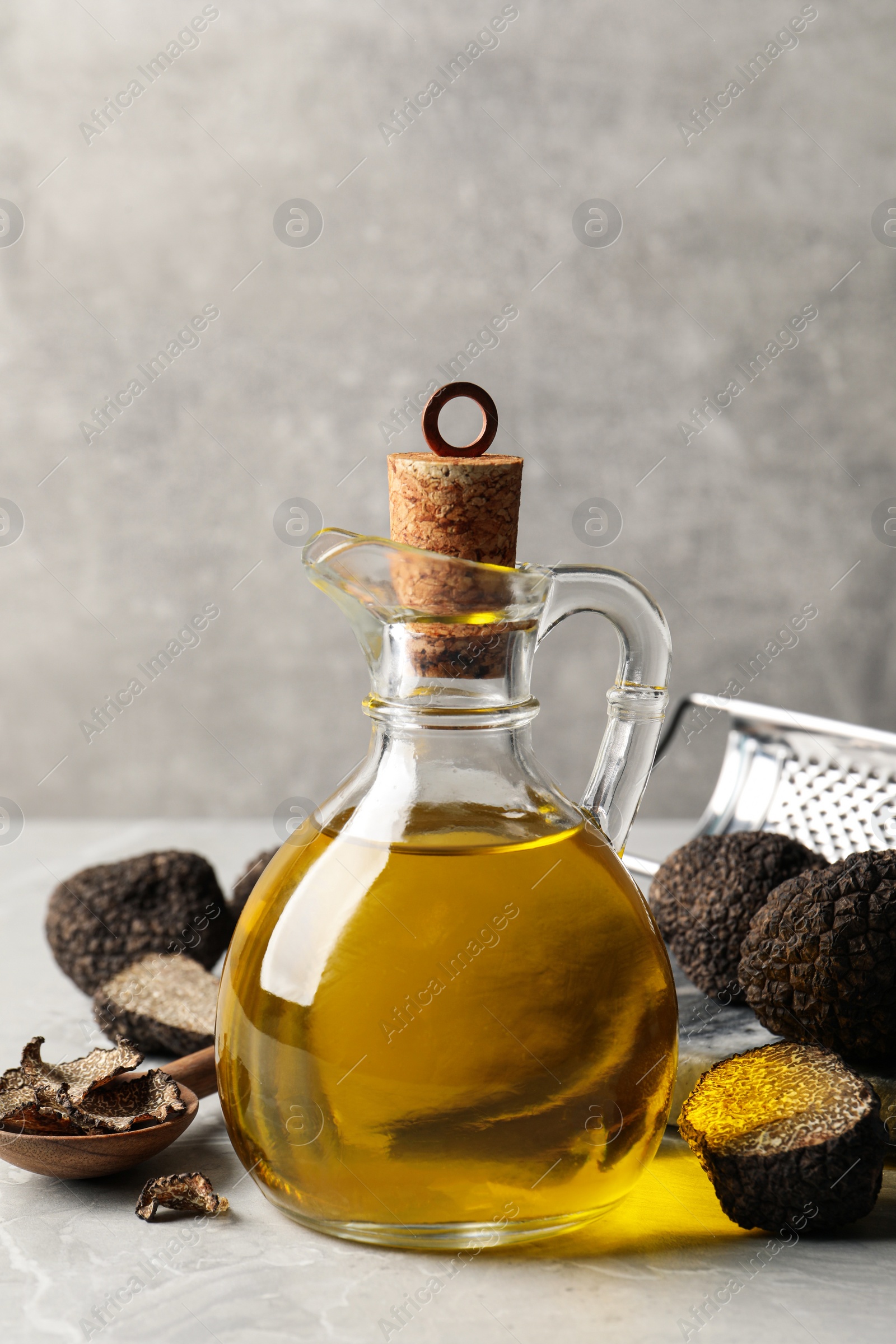 Photo of Fresh truffles and oil on light grey marble table