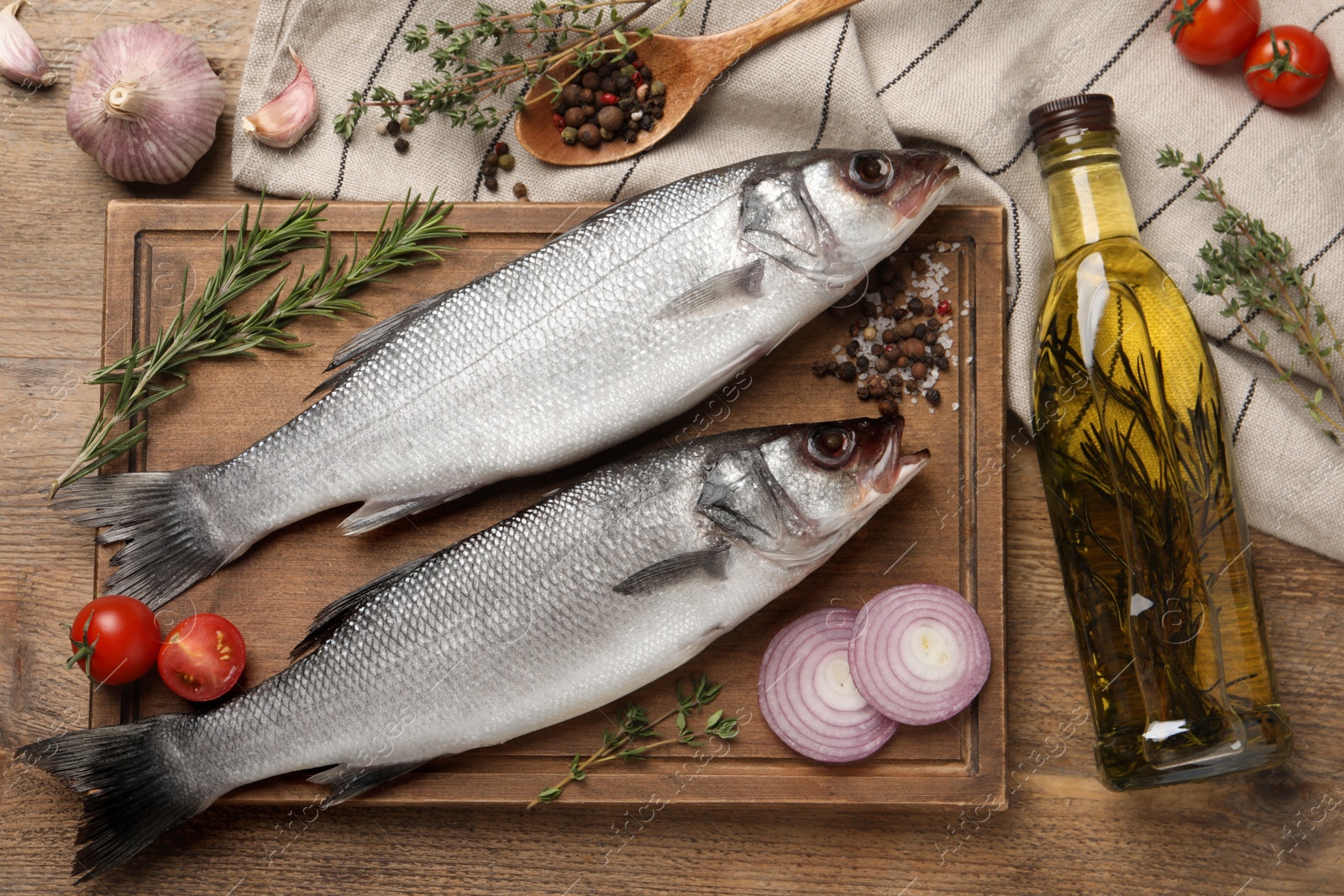 Photo of Sea bass fish and ingredients on wooden table, flat lay