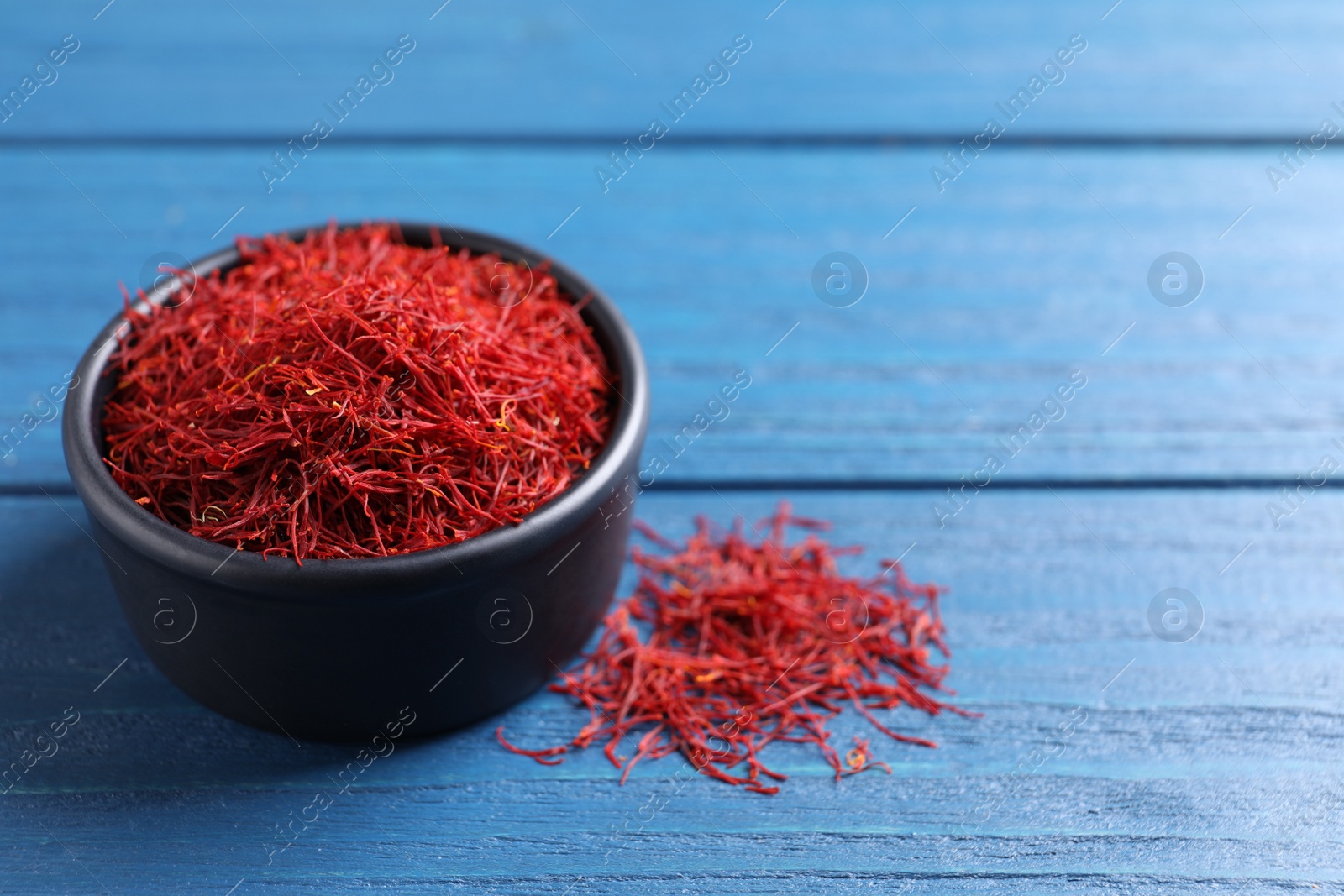 Photo of Dried saffron on blue wooden table, space for text