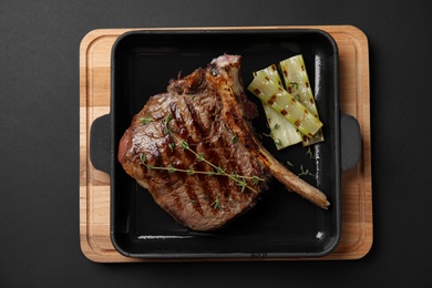 Photo of Grill pan with barbecued meat on black background, top view