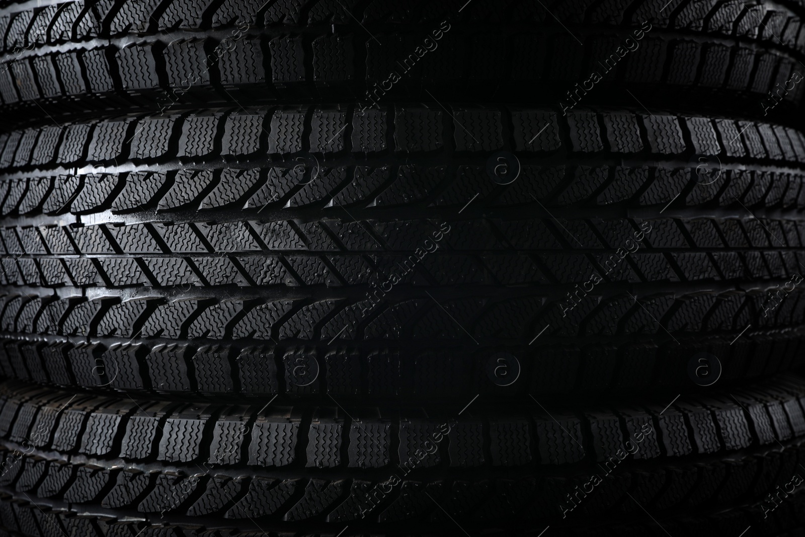 Photo of Stacked winter tires as background, closeup. Car maintenance