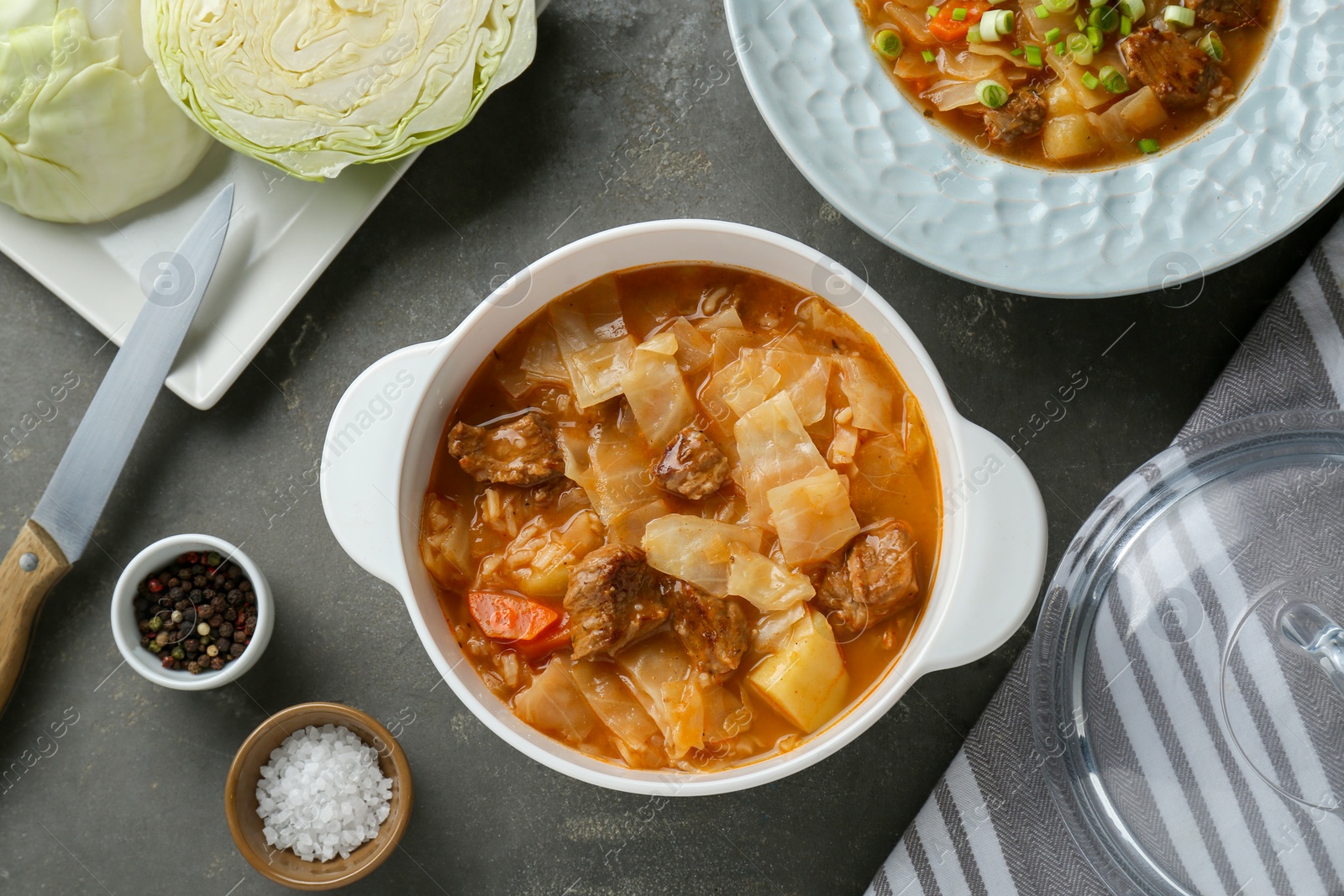 Photo of Tasty cabbage soup with meat and carrot served on grey table, flat lay