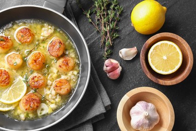 Photo of Delicious scallops with sauce in frying pan and ingredients on dark gray textured table, flat lay