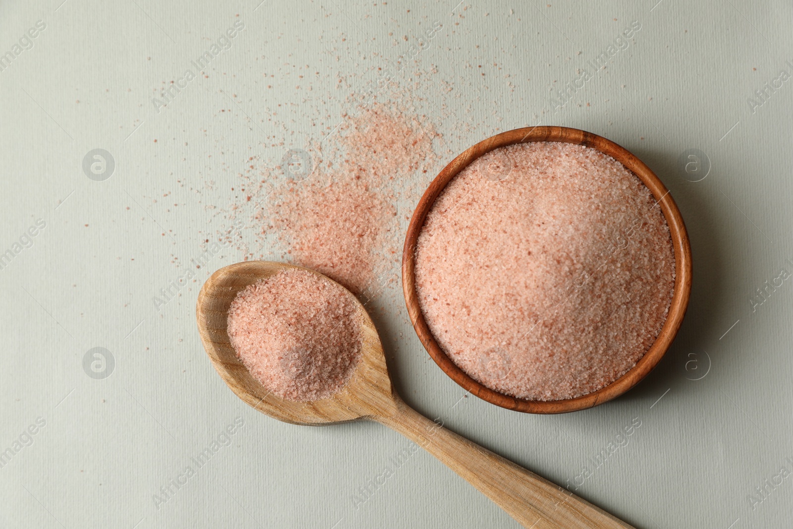 Photo of Himalayan salt in bowl and spoon on grey background, flat lay