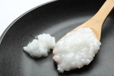 Photo of Frying pan with coconut oil and wooden spoon, closeup. Healthy cooking