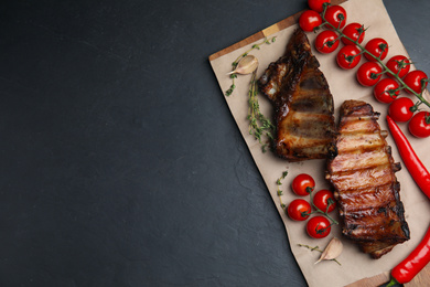 Photo of Tasty grilled ribs on black table, flat lay. Space for text