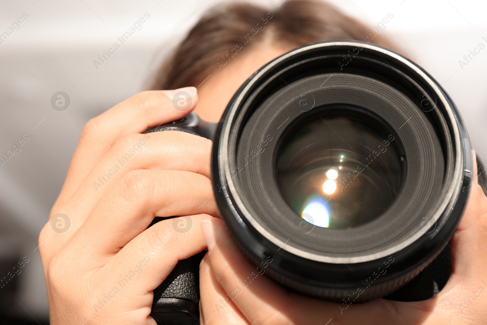 Photo of Female photographer with professional camera on blurred background, closeup