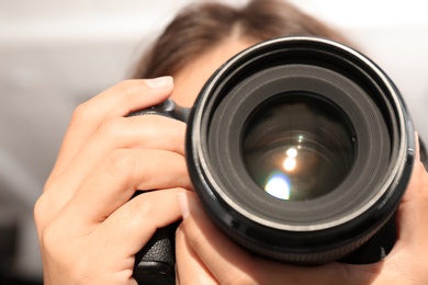 Female photographer with professional camera on blurred background, closeup