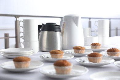 Photo of Many delicious muffins served on white table for coffee break