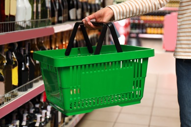 Woman with shopping basket in supermarket, closeup