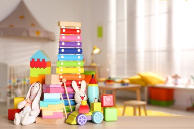 Image of Set of different bright toys on wooden table in children's room. Space for text