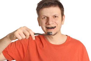 Photo of Man brushing teeth with charcoal toothpaste on white background
