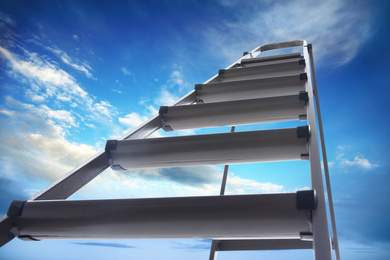 Metal stepladder against blue sky with clouds, low angle view