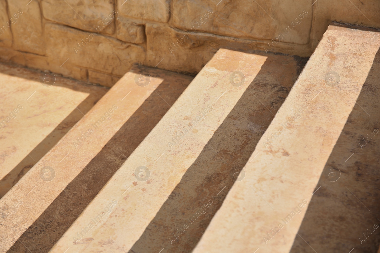 Photo of Closeup view of beautiful stone stairs near brick wall outdoors