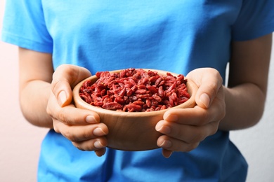 Woman holding bowl of red dried goji berries, closeup