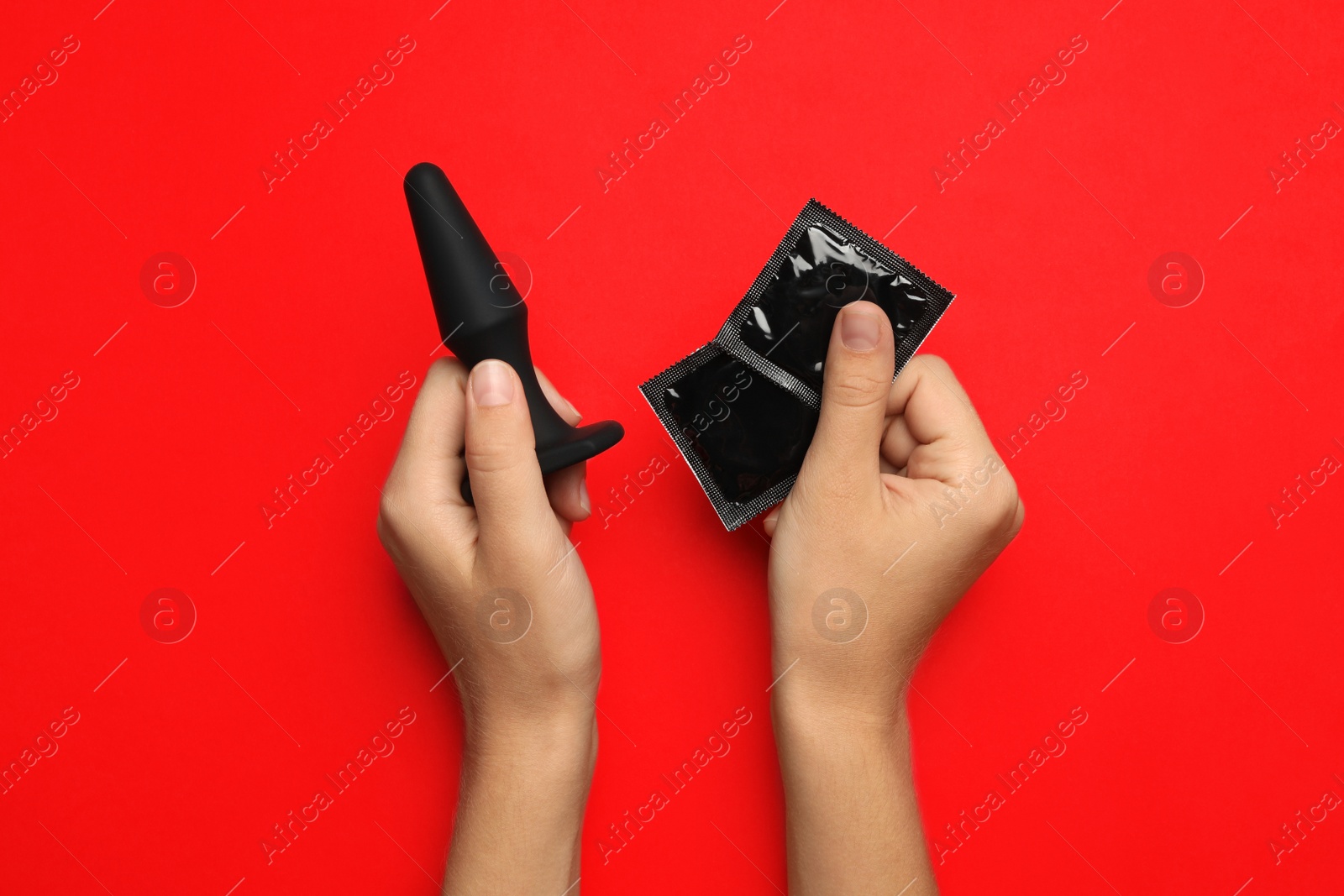 Photo of Woman with anal plug and condoms on red background, top view. Sex game