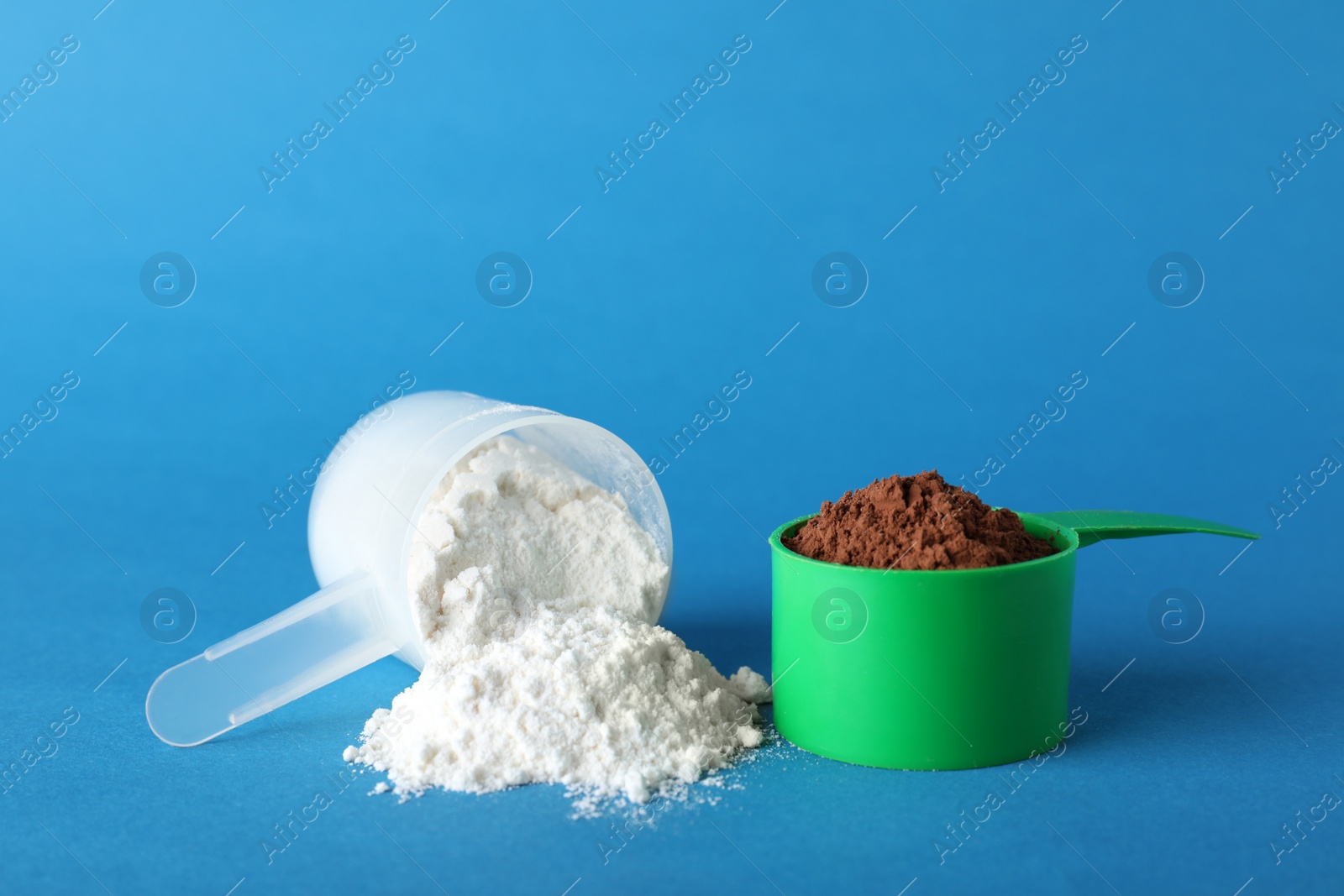 Photo of Scoops of different protein powders on blue background