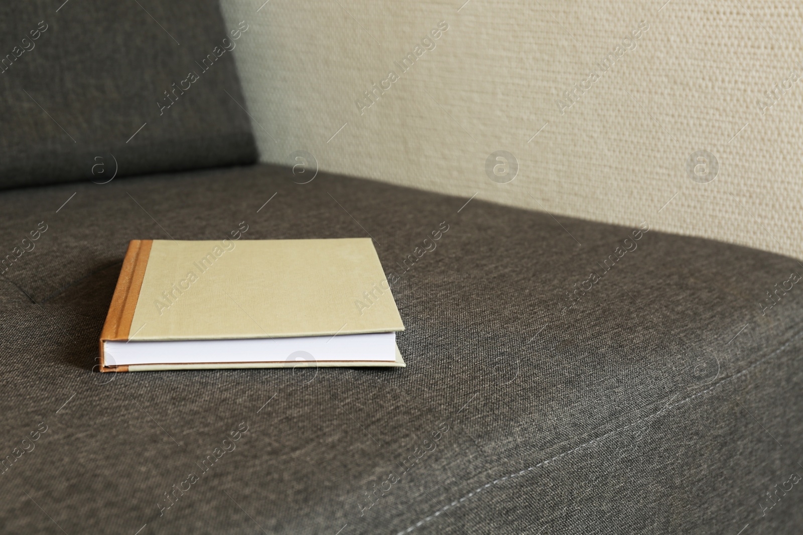 Photo of Hardcover book on grey sofa, space for text