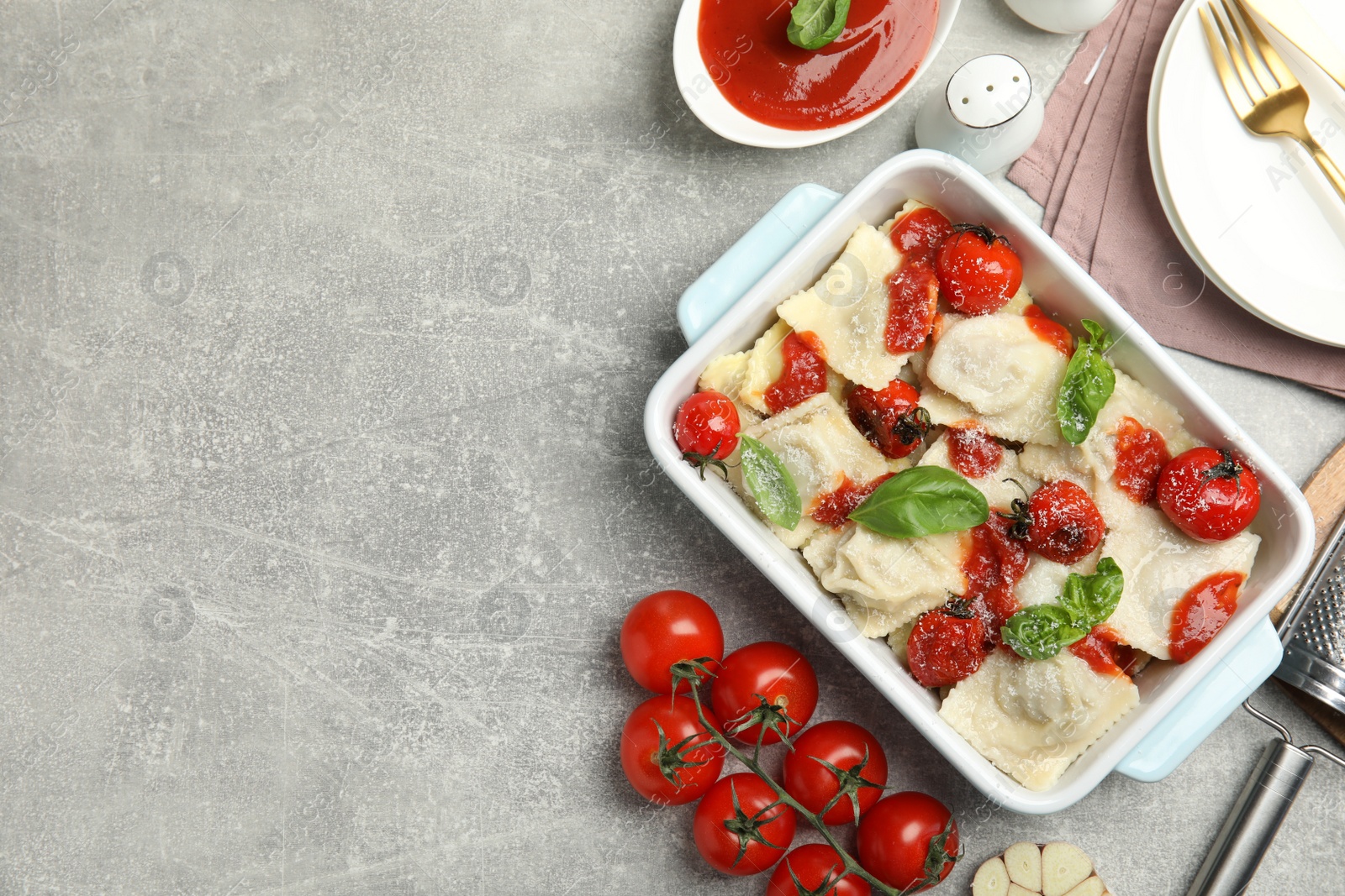 Photo of Tasty ravioli with tomato sauce served on grey table, flat lay. Space for text