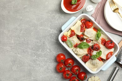 Tasty ravioli with tomato sauce served on grey table, flat lay. Space for text