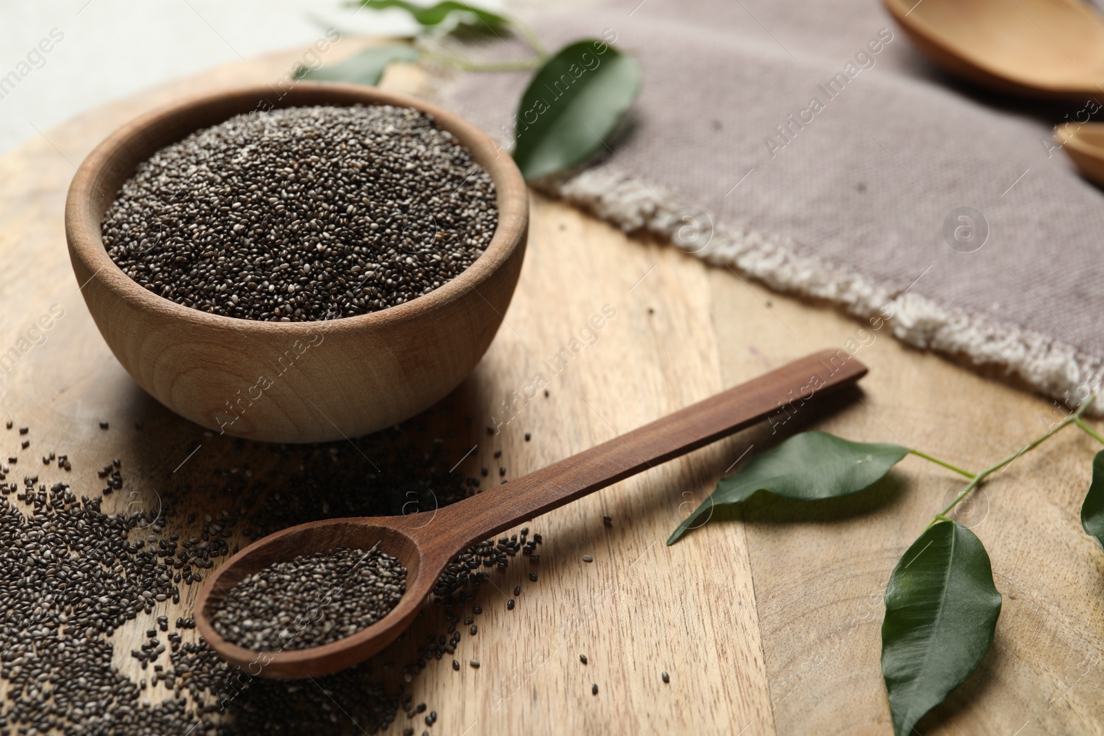 Photo of Chia seeds in bowl and spoon on wooden table