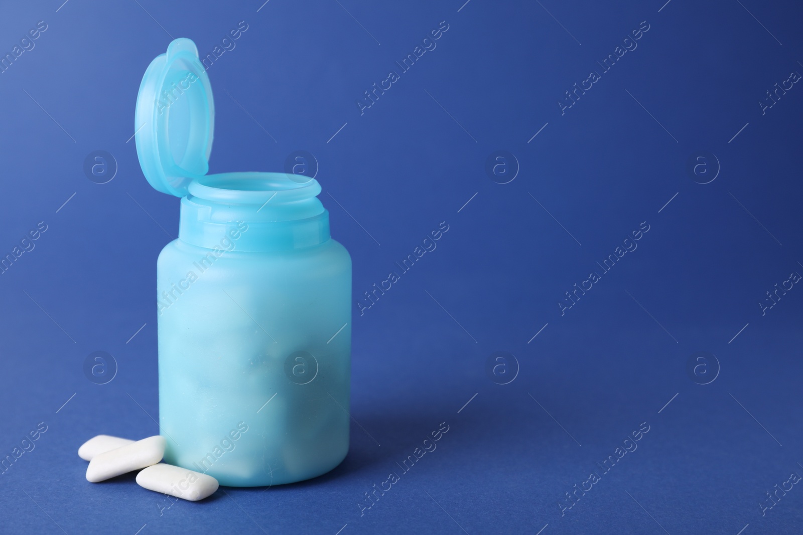 Photo of Jar with chewing gums on blue background. Space for text