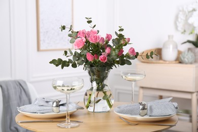 Place setting with pink roses on wooden table. Romantic dinner
