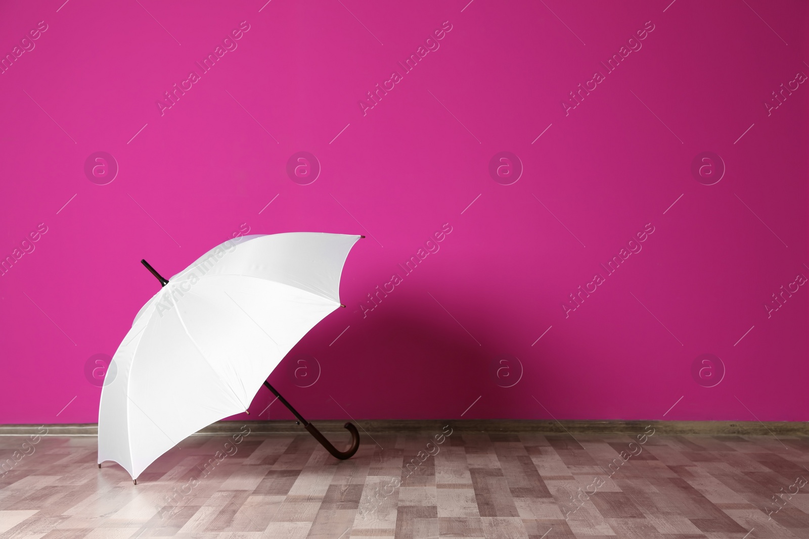 Photo of Beautiful open umbrella on floor near color wall with space for design