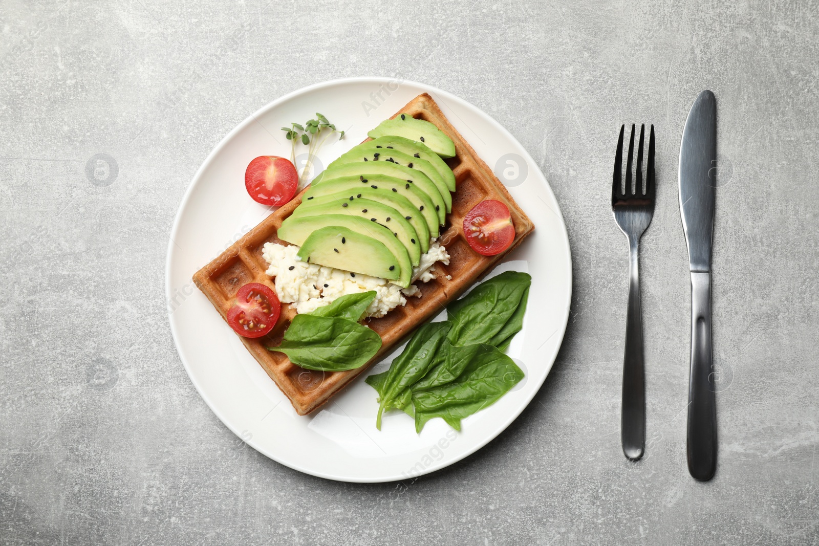 Photo of Fresh Belgian waffle with avocado, tomatoes and basil served for breakfast on light grey table, flat lay