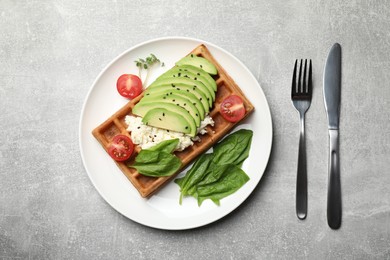 Fresh Belgian waffle with avocado, tomatoes and basil served for breakfast on light grey table, flat lay