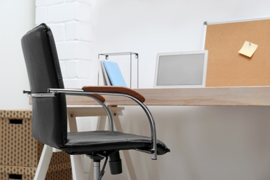 Stylish workplace interior with office chair and wooden table