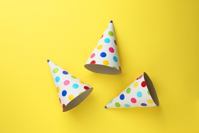 Beautiful party hats on yellow background, top view