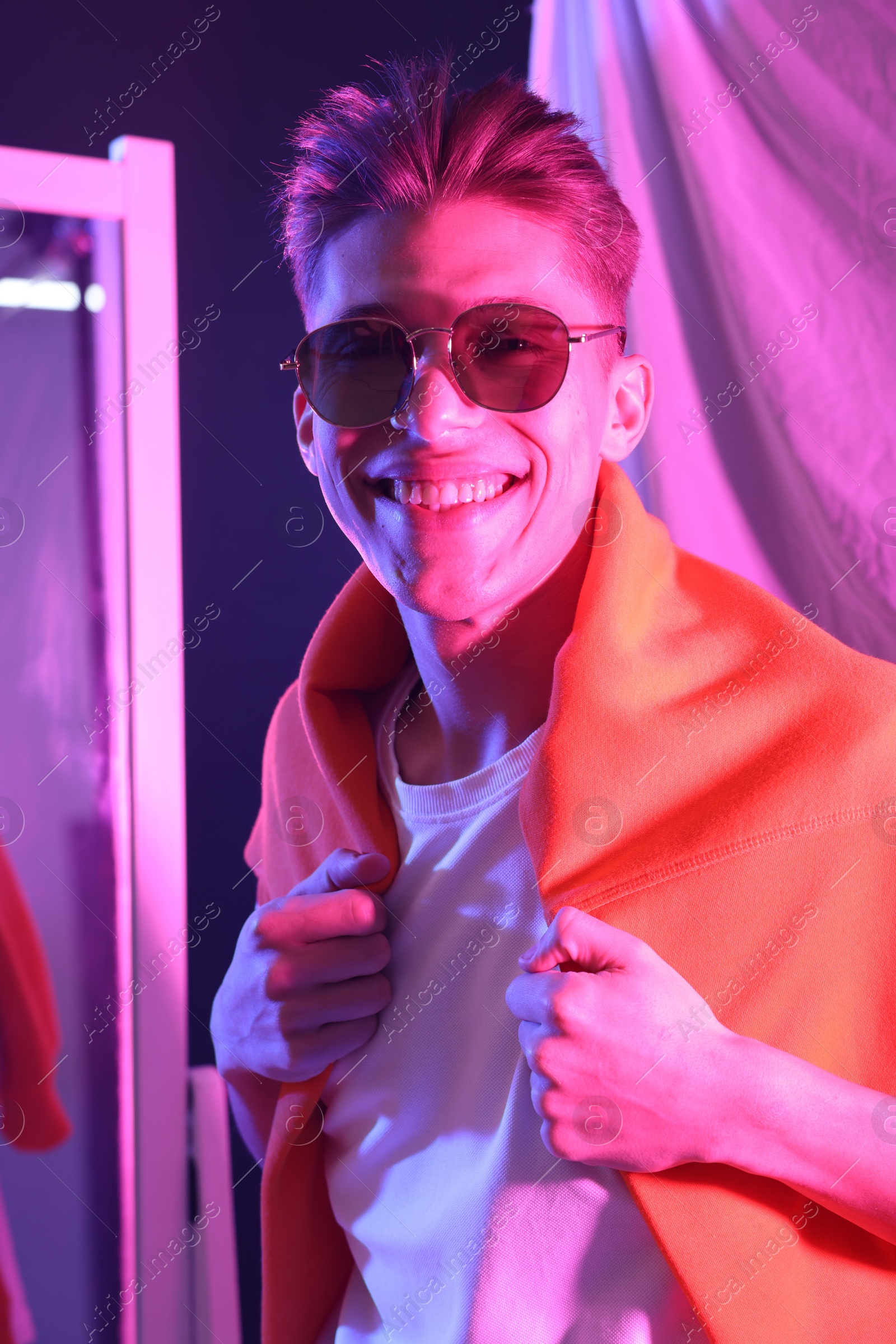 Photo of Stylish young man with sunglasses indoors in neon lights