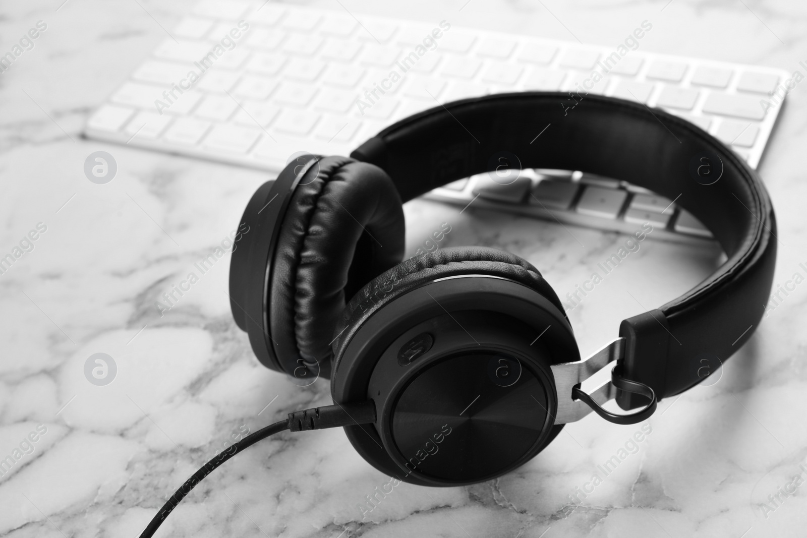 Photo of Modern headphones and computer keyboard on table