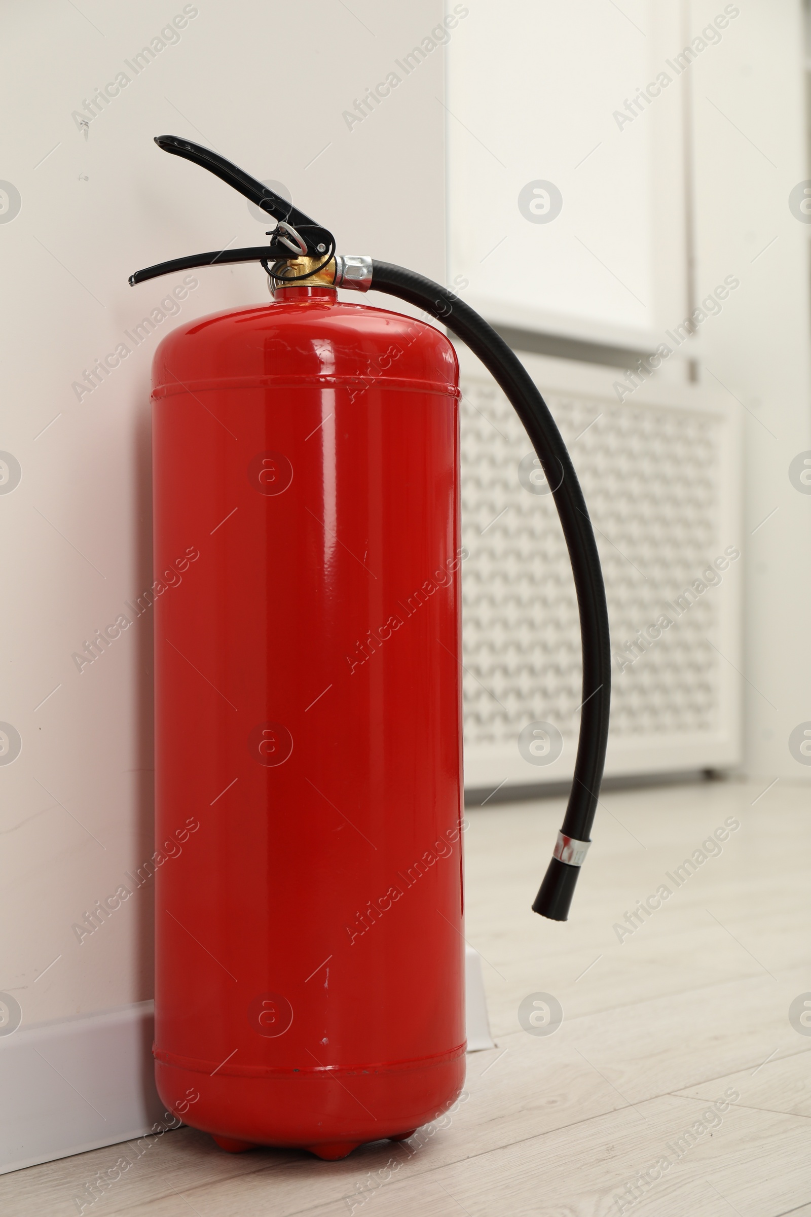 Photo of Fire extinguisher on floor near light wall indoors