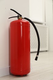 Fire extinguisher on floor near light wall indoors