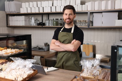 Happy seller at cashier desk in bakery shop