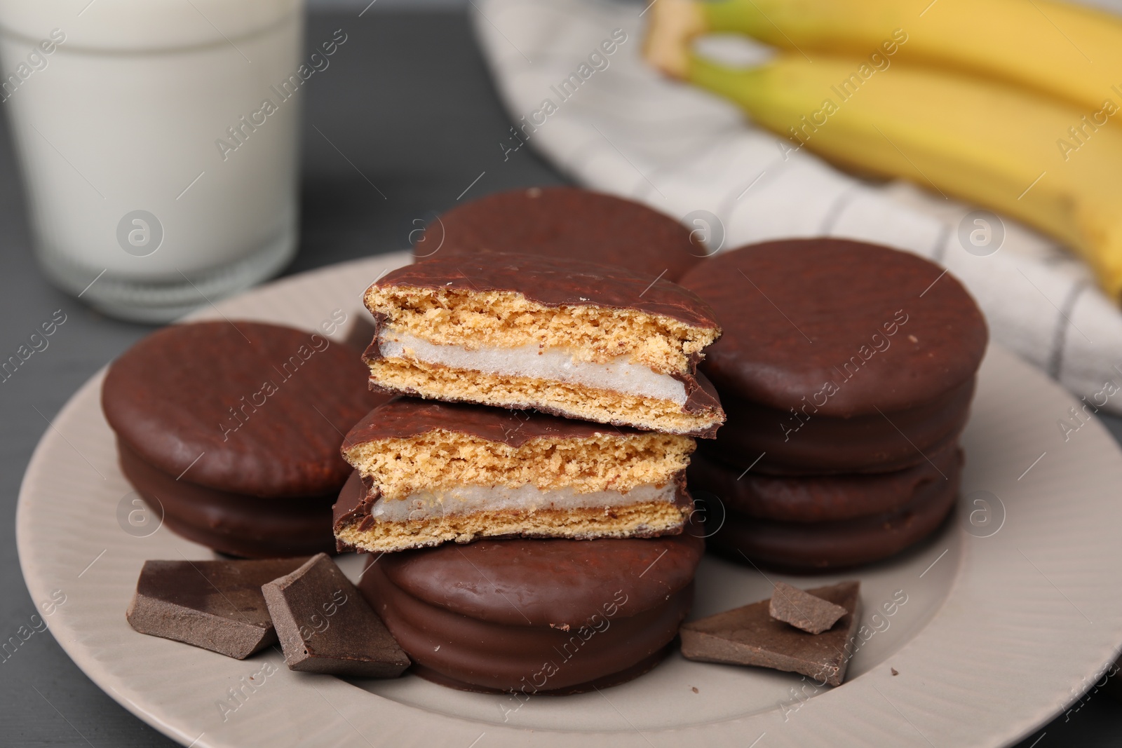 Photo of Plate with tasty banana choco pies and pieces of chocolate on table, closeup