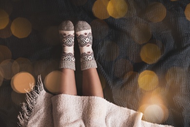 Woman in warm socks on knitted blanket, top view. Space for text