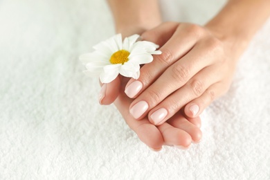Photo of Closeup view of woman holding flower on towel, space for text. Spa treatment